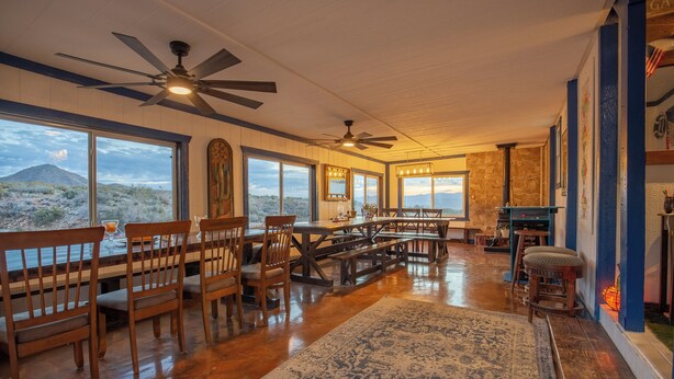 A spacious dining area with wooden furniture, large windows offering a view of a mountain, and ceiling fans. - The Prickly Pear: Experience Arizona Agritourism (Kingman)