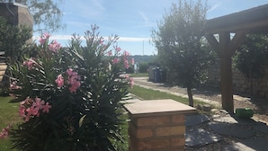 Un jardín con una estructura de ladrillo, un pérgola y un sendero.