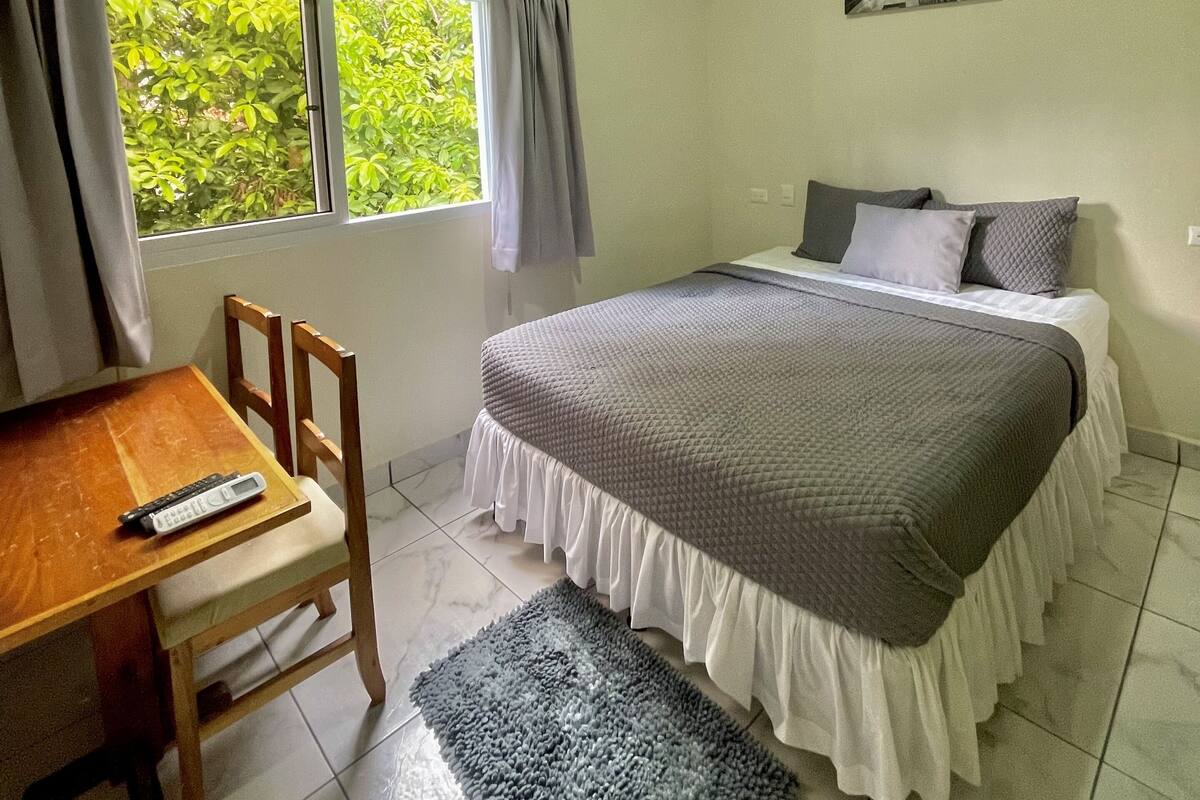 Un dormitorio con cama, escritorio y silla.