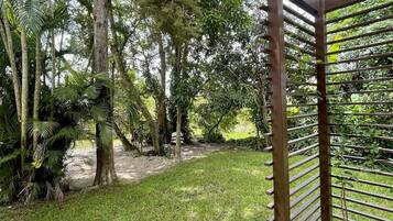 A covered outdoor area with a wooden pergola, stone pathway, and lush greenery.