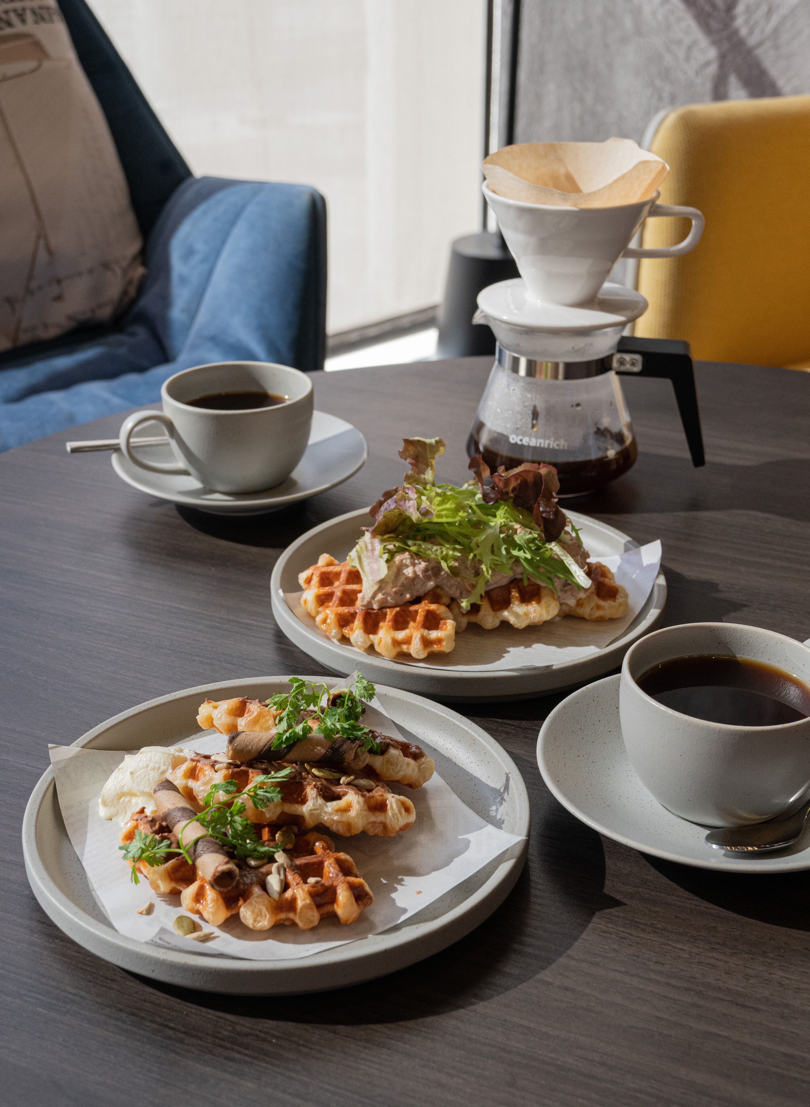 A table with waffles, coffee, and a coffee maker.