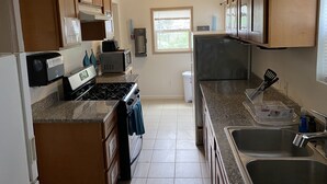 A kitchen with wooden cabinets, a stove, a microwave, and a refrigerator. - WHOLE Family - Barrette - Hostel (Sacramento)