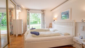Ein Schlafzimmer mit einem großen Bett, einem Nachttisch, einer Lampe und einem Fenster mit Vorhängen.