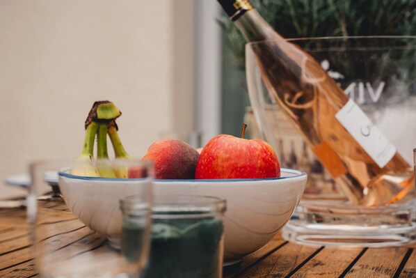 A wooden table with a bowl containing two apples and a bottle of champagne.