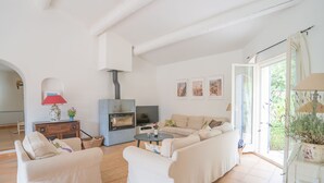 Ein geräumiges Wohnzimmer mit einer Sofagarnitur, einem Fernseher, einem Kamin und einem Essbereich mit Tisch und Stühlen.
