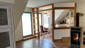 A modern kitchen with a central island, wooden beams, and a fireplace. - Varus vacation apartment in the Kalkriese recreation area surrounded by meadows and forests (Ostercappeln)