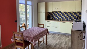 Cocina compacta con mesa, sillas y un televisor pequeño.