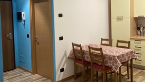 Un comedor con una mesa dispuesta para cuatro personas, sillas de madera y un mantel estampado.