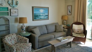 A living room with a sofa, armchair, coffee table, and decorative items including an anchor and a framed painting. - Gulf Front Condo, outdoor/ indoor pools, Large wrap around balcony, 3br/2ba (Orange Beach)
