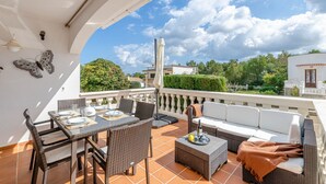 Una terrazza con un tavolo da pranzo, sedie, un divano e una farfalla decorativa sulla parete.