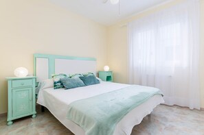 Une chambre à coucher avec un lit, des tables de chevet, une lampe et une fenêtre avec des rideaux.