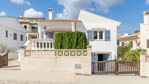 Un edificio bianco con un balcone, un cancello e un siepe.