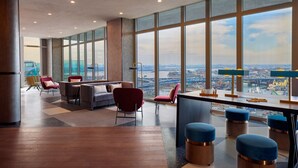 A spacious lounge area with large windows, a high ceiling, and a view of a cityscape. - Renaissance New York Flushing Hotel at Tangram (Flushing)