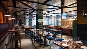 Un restaurante con techos altos, vigas a la vista y una variedad de opciones de asiento, incluyendo mesas y cabinas.