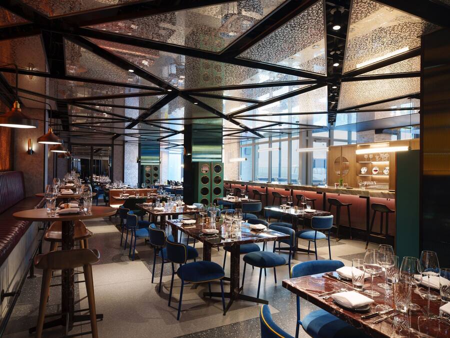 Ein Restaurant mit hohen Decken, freiliegenden Balken und einer Mischung aus Sitzgelegenheiten, darunter Tische und Sitzecken.