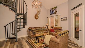 A living room with a spiral staircase, a mounted deer head, a sofa set, a coffee table, and a rug.