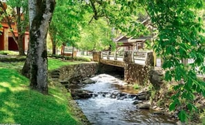 Surrounded by lush greenery, a serene stream flows beneath a stone bridge.