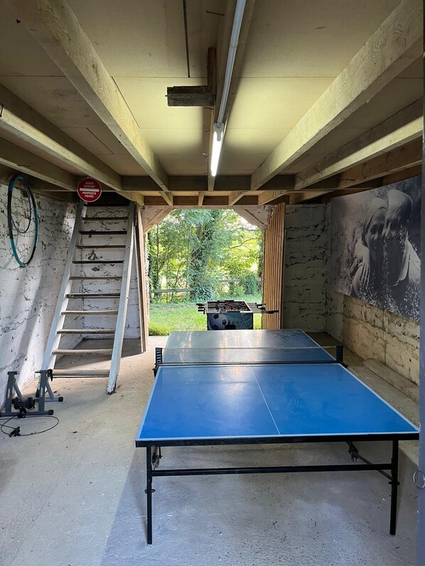 A ping pong table in a room with a staircase leading to a balcony.
