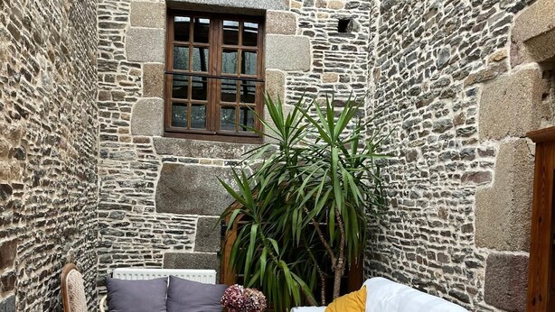 Una habitación acogedora con paredes de piedra, muebles de mimbre, una mesita y una ventana.