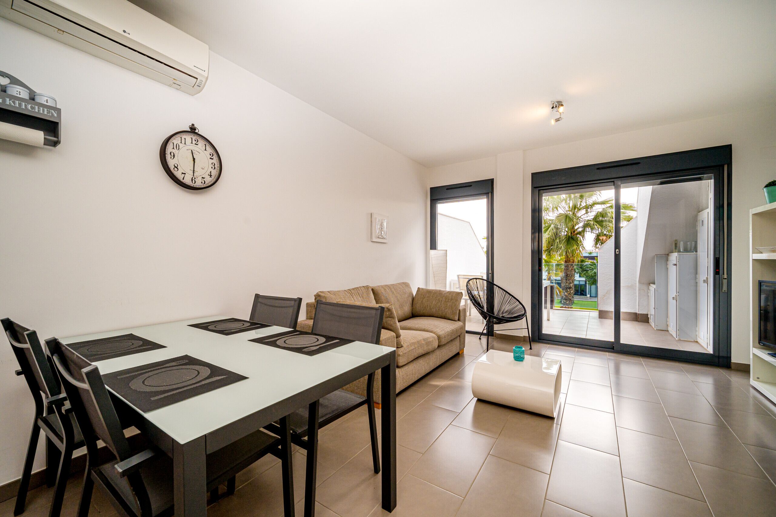 A modern living room with a dining table, sofa, and a view to the outside.