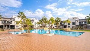 Un hotel moderno con una amplia piscina exterior, palmeras y arquitectura contemporánea.