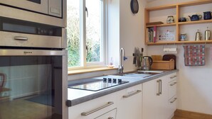 A modern kitchen with a built-in oven, a sink, and a window with a view of greenery.