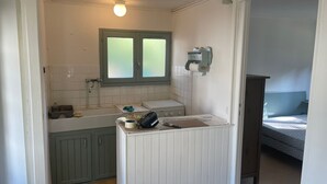 A compact bathroom with a window, a toilet, and a sink with various toiletries.