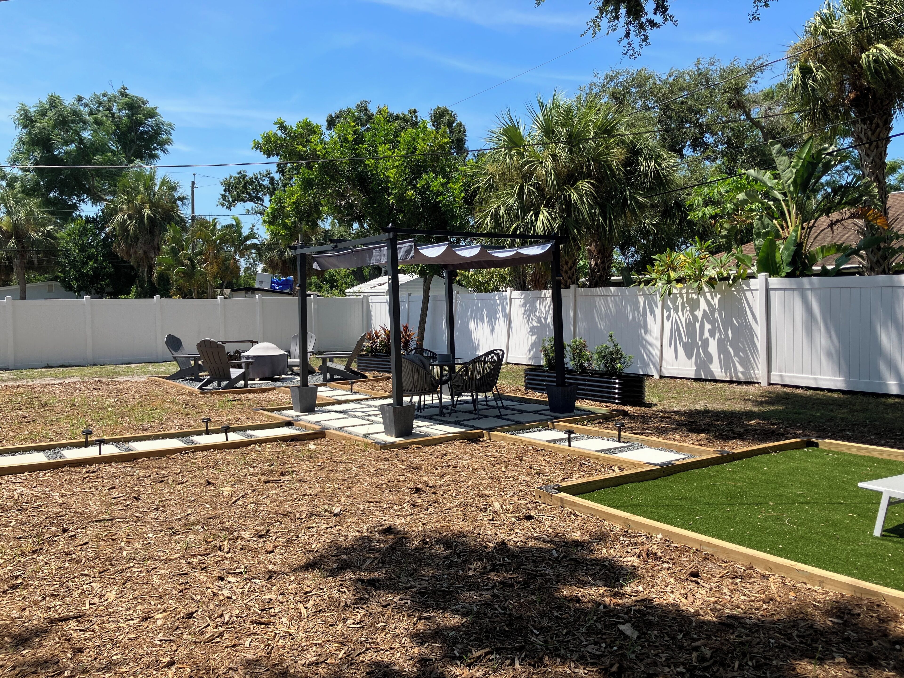 Un jardin avec une pergola, un espace salon extérieur et un petit coin aménagé.