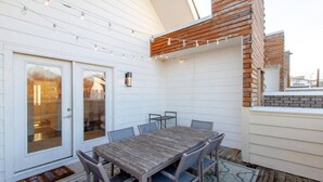 Un espace patio avec une table et des chaises en bois, une porte vitrée et un mur en briques.