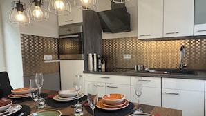 A modern kitchen with white cabinets, a black countertop, and a wooden dining table set for a meal.