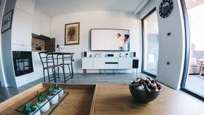 Una cuina moderna amb armaris blancs, una zona de menjador amb taula de fusta, i una finestra gran que ofereix vistes a l'exterior.
