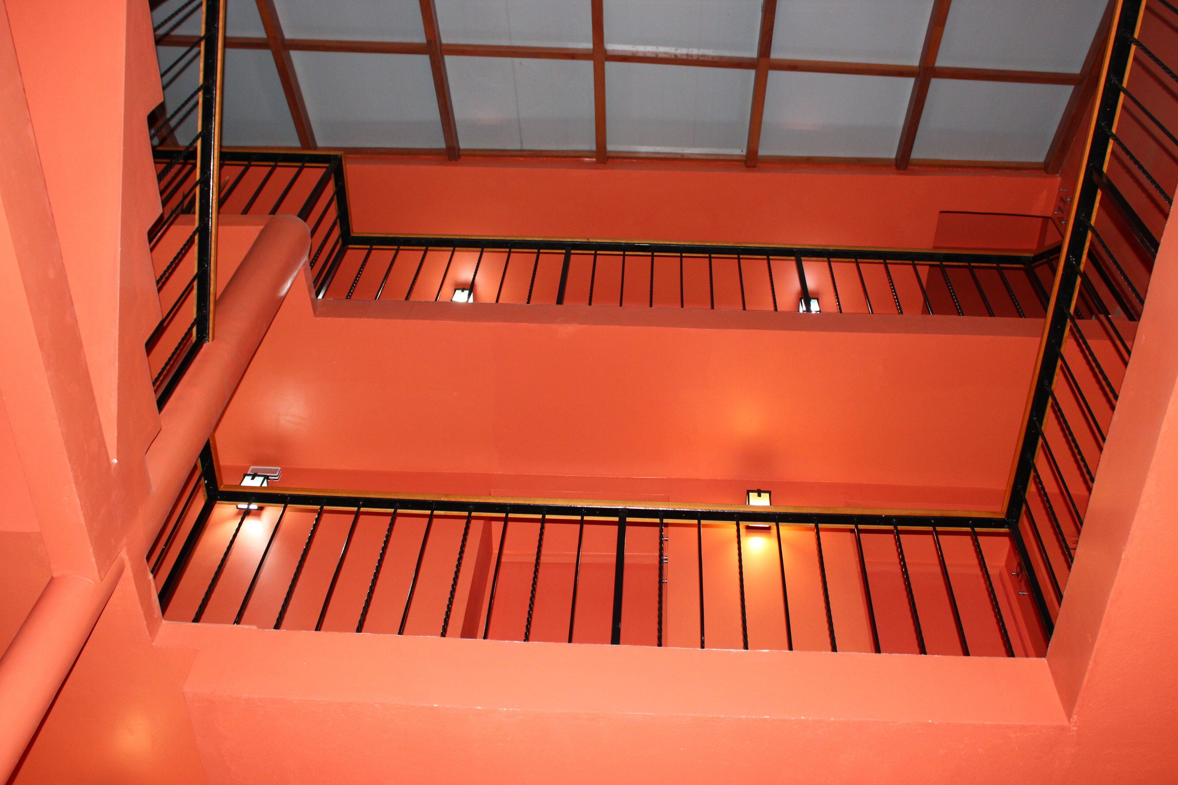 A multi-level interior with orange walls and metal railings.