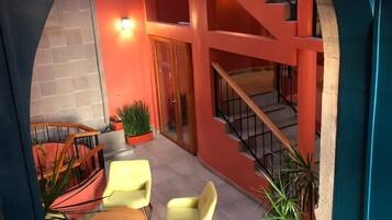 Un interior moderno con una paleta de colores rojo y azul, que incluye una escalera, zona de estar con sillas y plantas en macetas.