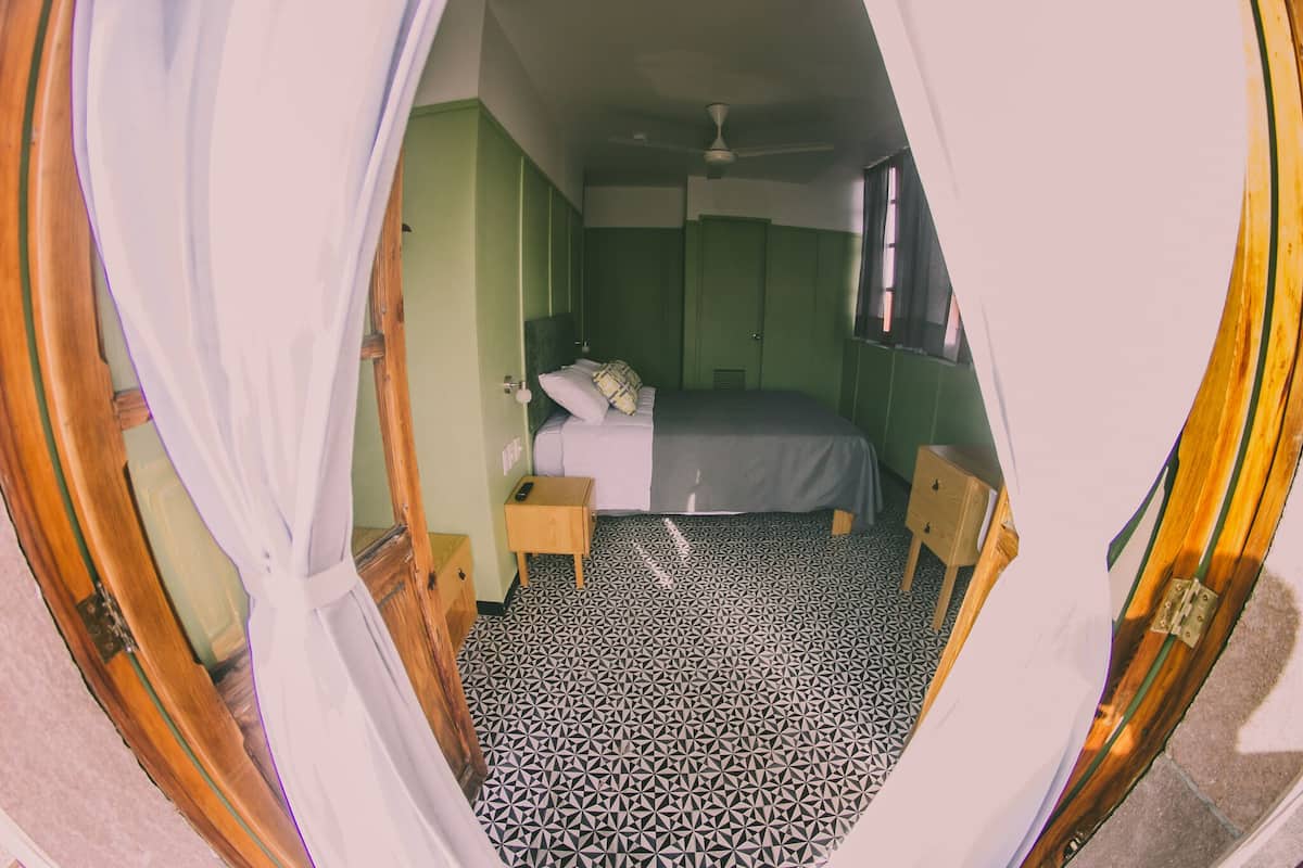 Een slaapkamer met een bed, nachtkastjes, een plafondventilator en een vloer met patroon.