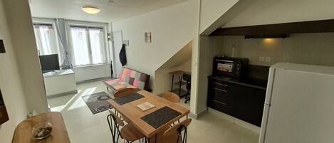 Un espacio habitable compacto con comedor, kitchenette y sofá.