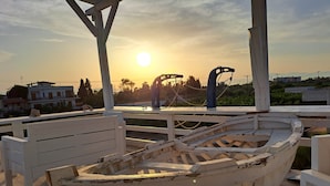 A boat on a wooden deck with a sunset in the background. - Nautilus (Aegina)