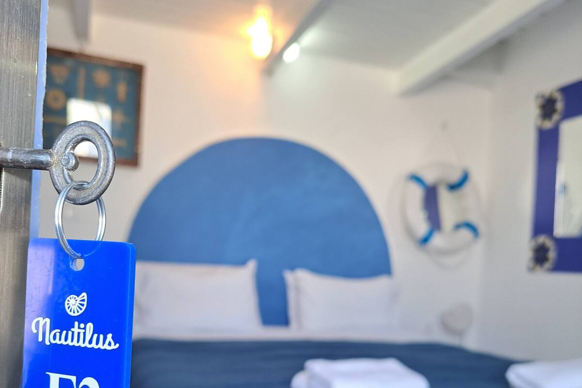 A hotel room with a large bed, a headboard, and a keychain with the hotel name and room number.