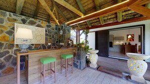 Una zona de bar con pared de piedra, techo de madera y dos taburetes verdes.