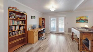 A room with a wooden desk, a computer, a bookshelf, and a door leading to a balcony. - NEW Updated, Private 3/2 Home(King)Near Balloon Fiesta Park, Quiet Neighborhood! (Albuquerque)
