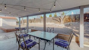 An outdoor patio area with a glass enclosure, a table, chairs, and a bench. - NEW Updated, Private 3/2 Home(King)Near Balloon Fiesta Park, Quiet Neighborhood! (Albuquerque)