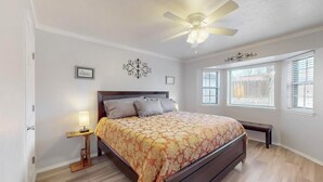 A bedroom with a bed, a ceiling fan, a bedside table with a lamp, and a window with blinds. - NEW Updated, Private 3/2 Home(King)Near Balloon Fiesta Park, Quiet Neighborhood! (Albuquerque)