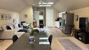 A spacious living room with a dining table, a sofa, a TV, and a kitchen area with a refrigerator and microwave.