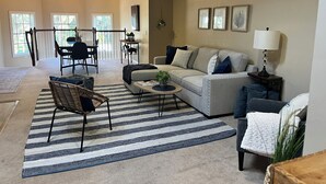 A spacious living room with a sofa, armchairs, a coffee table, and a dining area with a table and chairs.