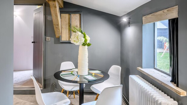 Un espace repas moderne avec une table ronde, des chaises blanches et un vase de fleurs.