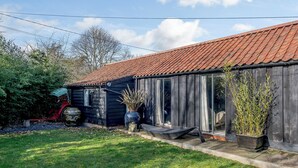 Une maison en bois avec un toit recouvert de tuiles rouges, une porte en verre et un petit porche.