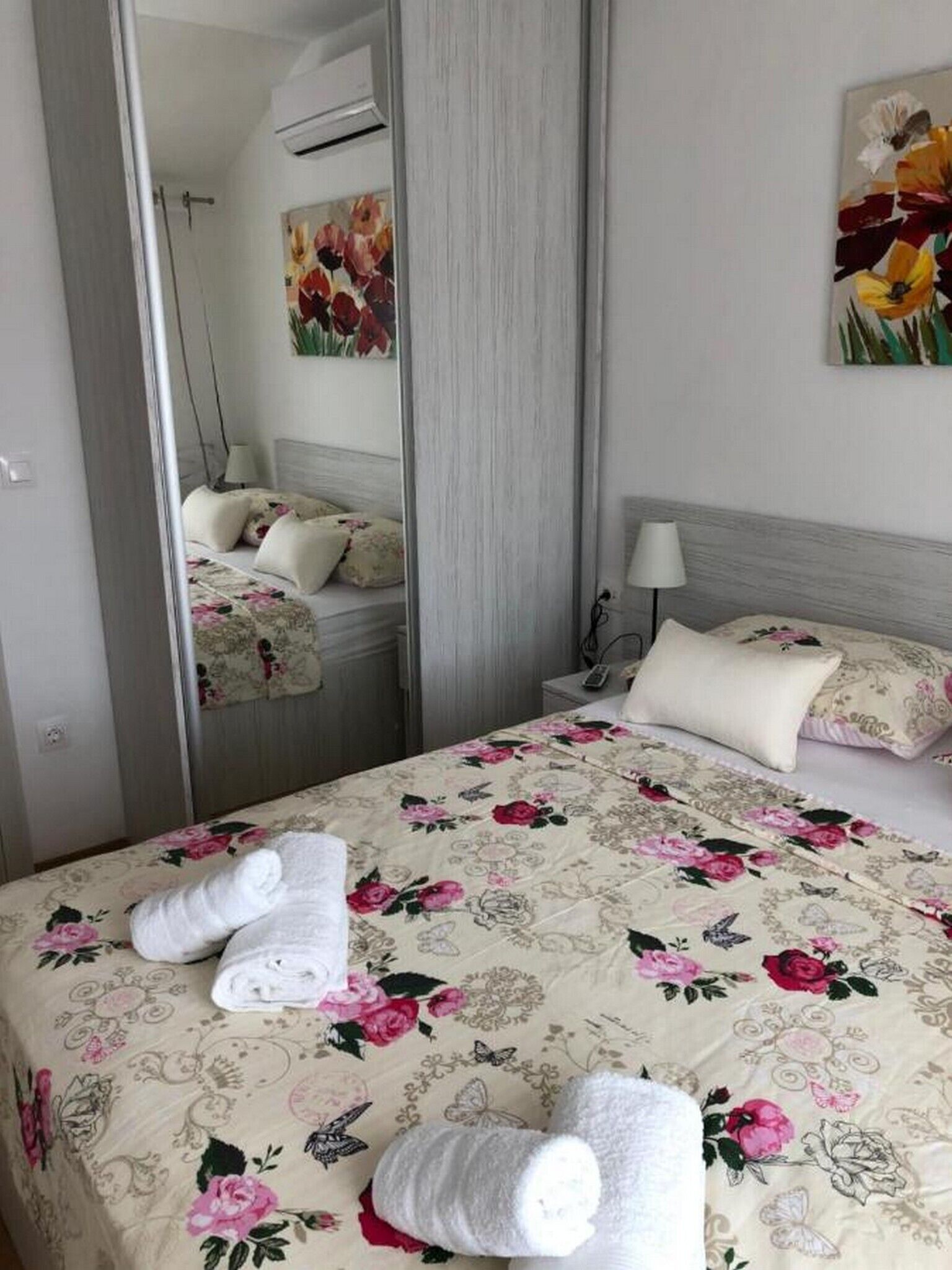 A hotel room with a bed, a nightstand, a lamp, and a mirror.