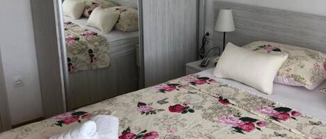 A hotel room with a bed, a nightstand, a lamp, and a mirror.