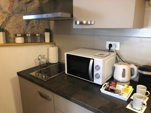 Una kitchenette compacta con microondas, hervidor y cafetera.