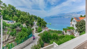A coastal view with a road leading to a beach, surrounded by greenery and buildings. - Apartments Ivo - Comfort One bedroom apartment with terrace and sea view (A3) (Postira)