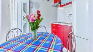 A kitchen with red cabinets, a white refrigerator, and a colorful tablecloth. - Apartments Ivo - Comfort One bedroom apartment with terrace and sea view (A3) (Postira)